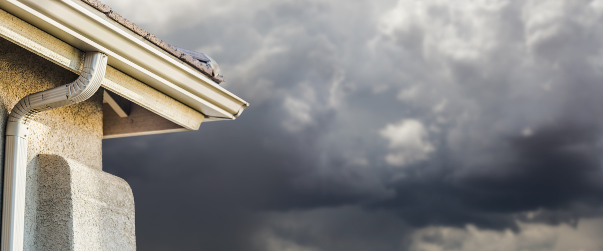 Corner of a home's roof with storm clouds in the background.
